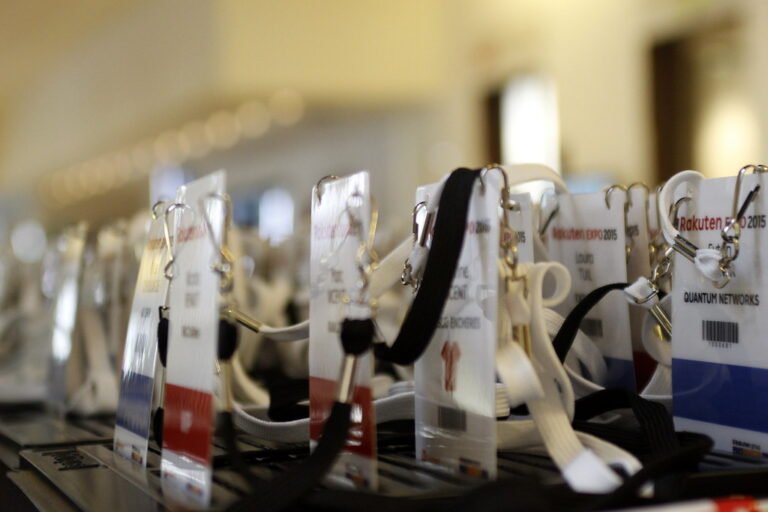 Plusieurs badges nominatifs et cordons d’accès posés sur une table lors d’un événement professionnel.