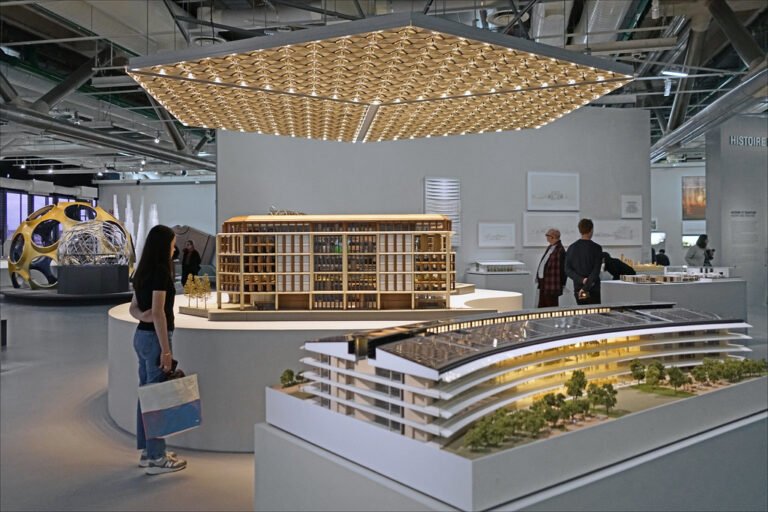 Visiteurs observant des maquettes architecturales et une installation dans un espace d’exposition.