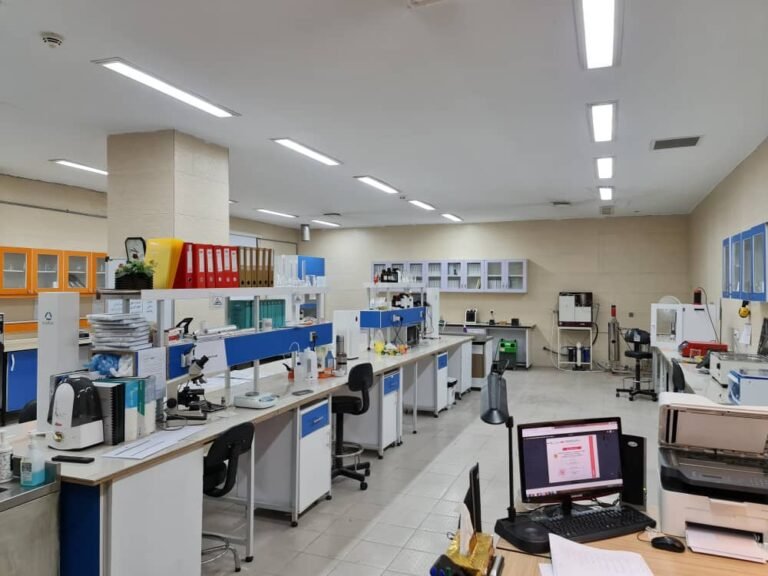 Laboratoire de recherche aménagé avec paillasses, microscopes, appareils scientifiques, classeurs et ordinateurs.