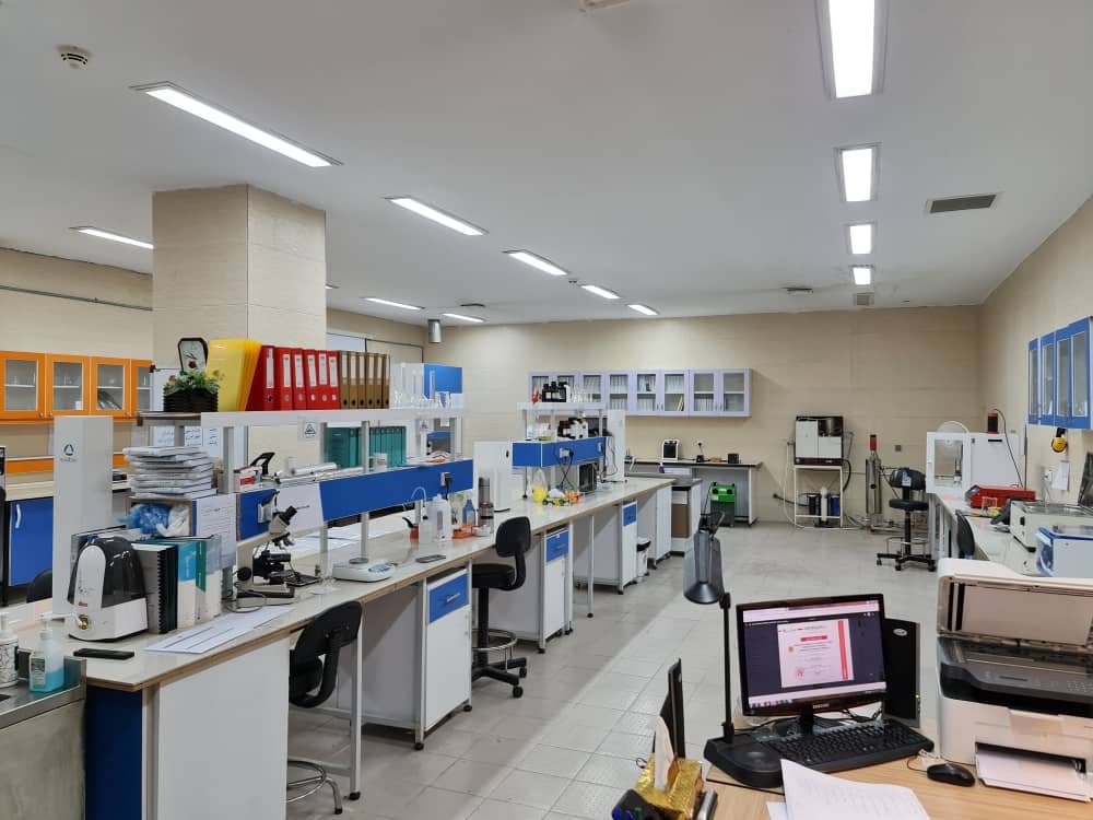 Laboratoire de recherche aménagé avec paillasses, microscopes, appareils scientifiques, classeurs et ordinateurs.