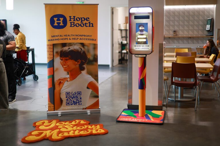 Borne interactive « Hope Booth » installée dans un espace intérieur, à côté d’une affiche présentant un exercice de respiration et des messages sur la santé mentale.