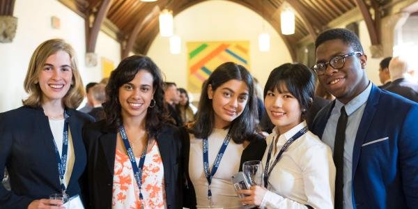 Groupe diversifié de jeunes adultes portant des badges, réunis dans un intérieur lors d’un événement.