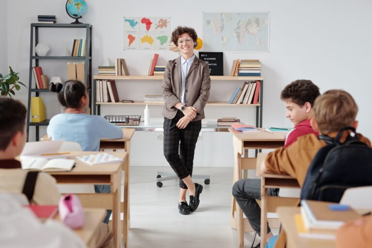 Une enseignante se tient devant des élèves assis à leurs pupitres dans une salle de classe.